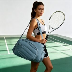 Female Athlete Carrying Blue Racket Tote over Shoulder and Holding Tennis Racket on Green Indoor Tennis Court - Fmosbag - Oem Bag Manufacturer & Custom Bag Factory