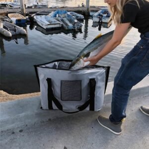 Woman Loading a Large Yellowtail Fish into an Insulated Fish Bag at a Marina Dock with Small Boats Behind - Fmosbag - Oem Bag Manufacturer & Custom Bag Factory